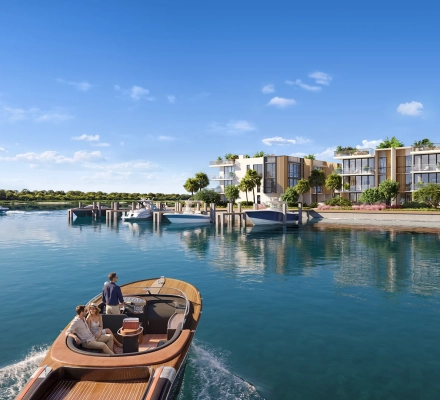 Luxury waterfront residences beside a marina with boats and a wooden motorboat on calm blue water.