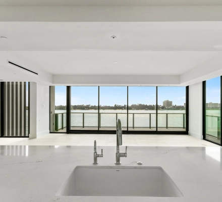 Kitchen sink facing open living area and waterfront windows