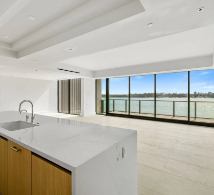 Kitchen island and open living room facing a waterfront balcony