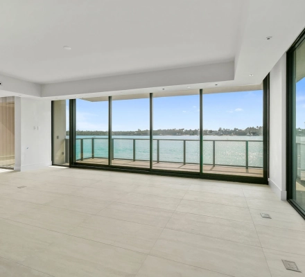 Empty living room with corner balcony and blue water view