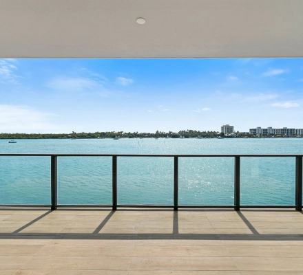 Covered balcony with tan tile and sunlit blue water view