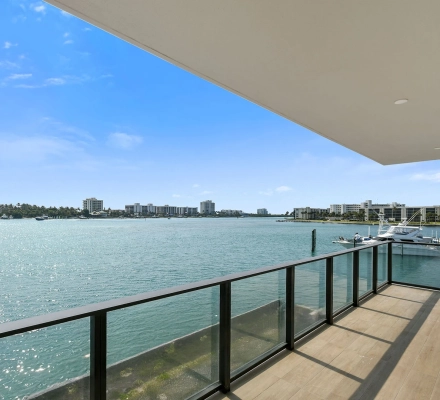 Close balcony railing view of turquoise water and shoreline
