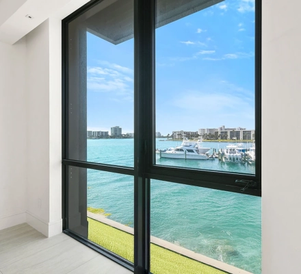 Empty bedroom with tall window overlooking marina water