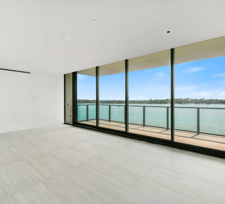 Open living room with glass wall facing waterfront balcony