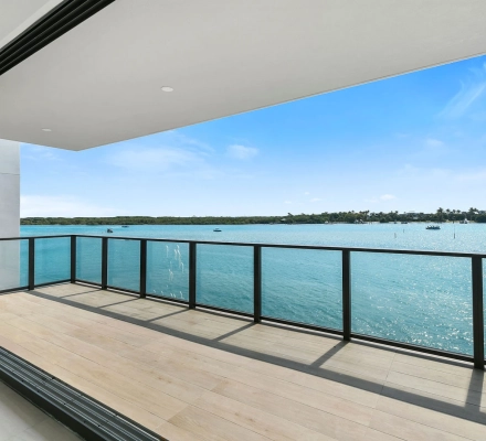 Covered balcony with black railing overlooking blue bay