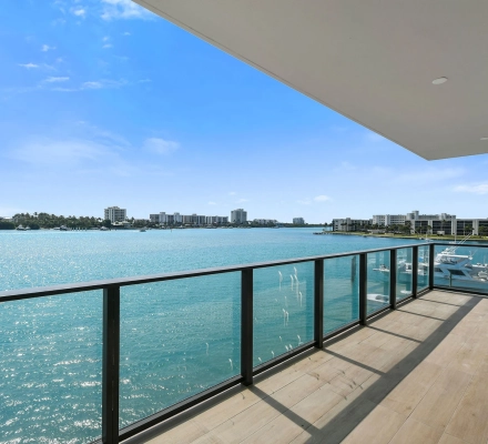 Glass railing balcony above turquoise water and marina