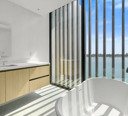 Freestanding tub beside vertical fins and water view