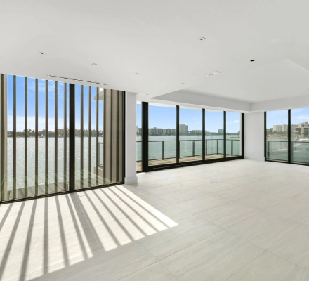 Empty corner living room with floor-to-ceiling waterfront windows